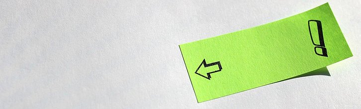 Post-it, auf das ein Ausrufezeichen und ein Pfeil gemalt sind