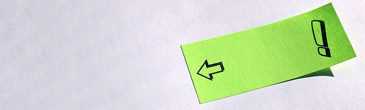Post-it, auf das ein Ausrufezeichen und ein Pfeil gemalt sind